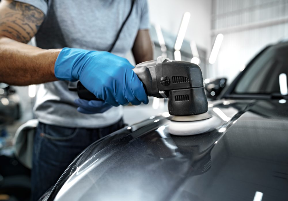 Car detailing. Male hands with orbital polisher in auto repair shop, close up